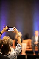 Konferensdeltagare som tar bild med sin mobiltelefon mot scenen